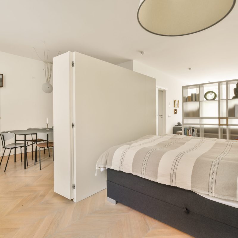 a bedroom with a bed, desk and mirror on the wall next to the bed is a small table in front of it